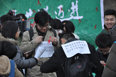 大學生志愿者們在活動現場別上象征艾滋病防治的紅絲帶