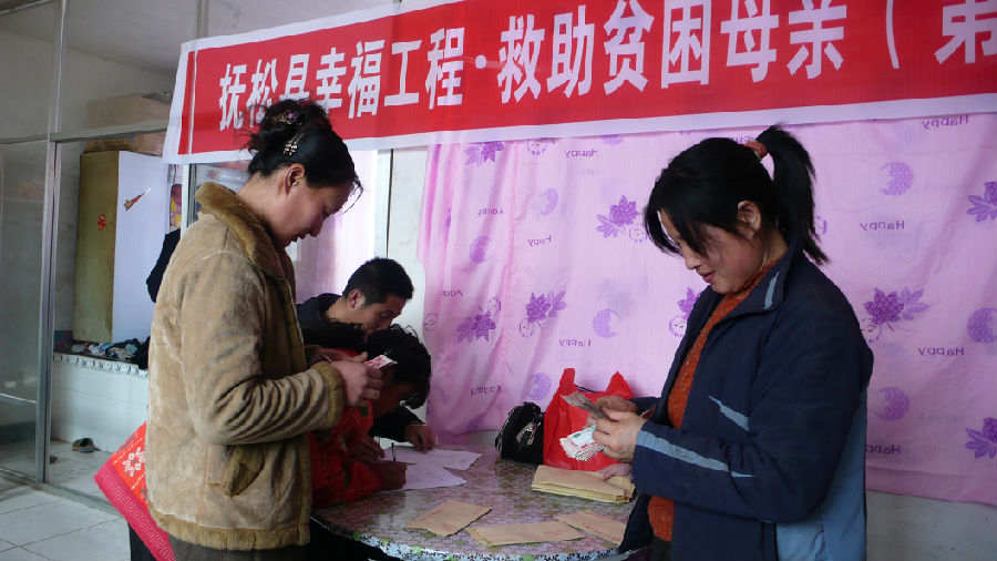 圖為慶升村貧困母親王秀琴高興地領到了5000元救助款