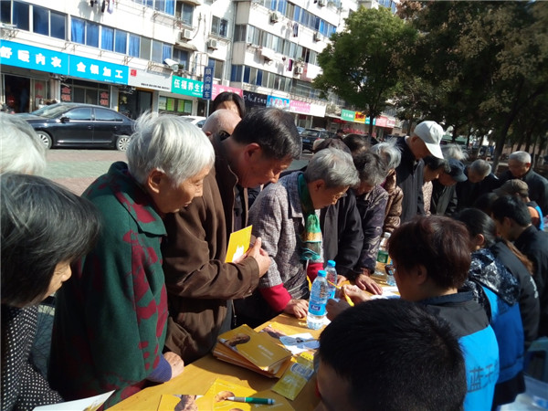 1509335547825952.jpg 老人排隊咨詢,領取黃手環、定位帖與宣傳資料.jpg